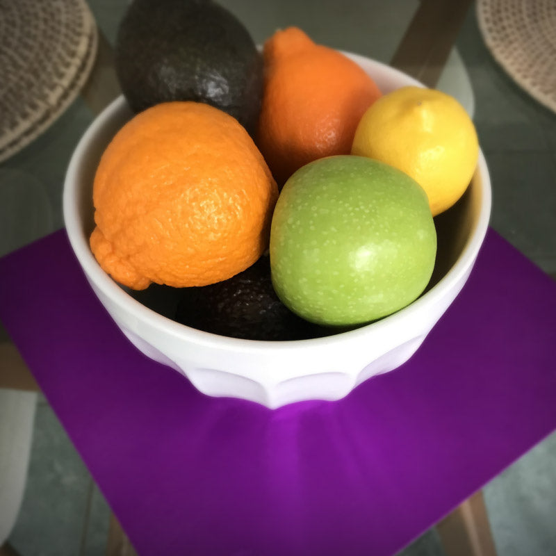 Tesla purple plate under fruit bowl on table