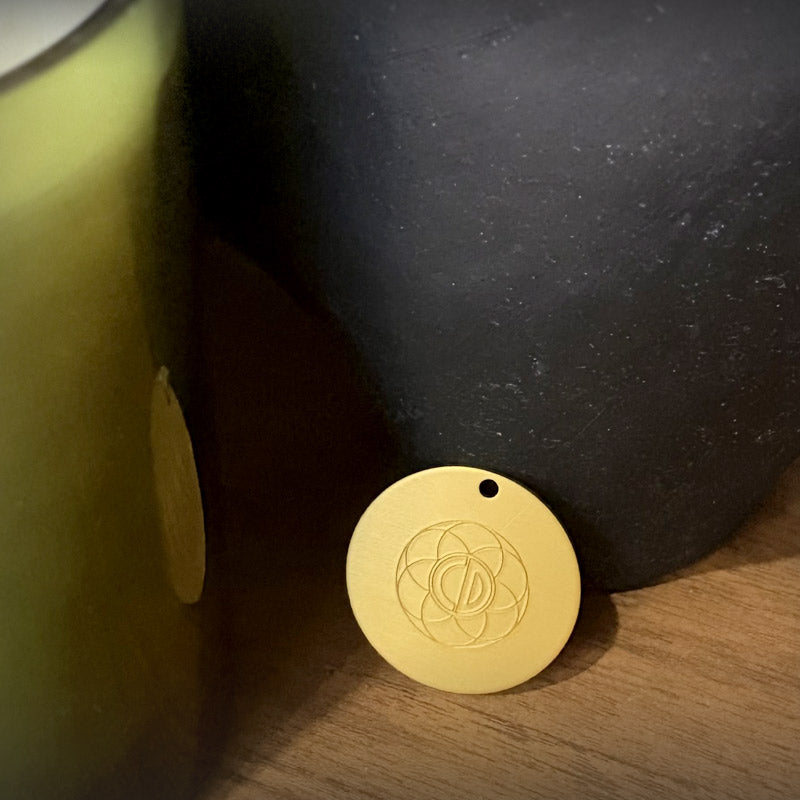 Auric Illumination Disc.  Gold pendant with a circular design on a dark surface