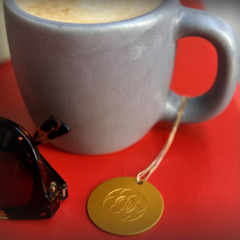 Auric Illumination Disc. Gray mug with a gold tag on a red surface